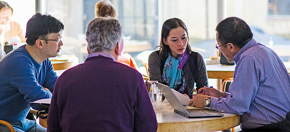 A group of scholars collaborating around a table.